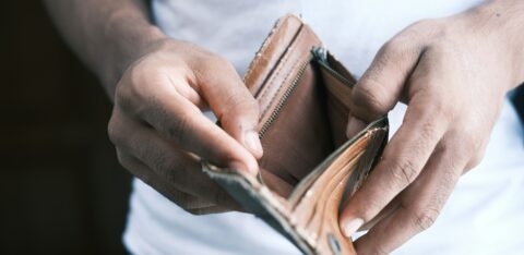Person holding an open, empty wallet with both hands.