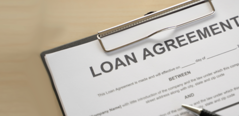 Close-up of a loan agreement form on a clipboard with a pen nearby.