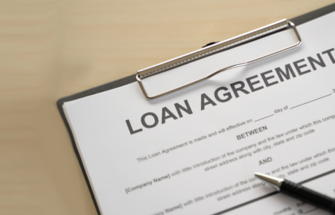Close-up of a loan agreement form on a clipboard with a pen nearby.