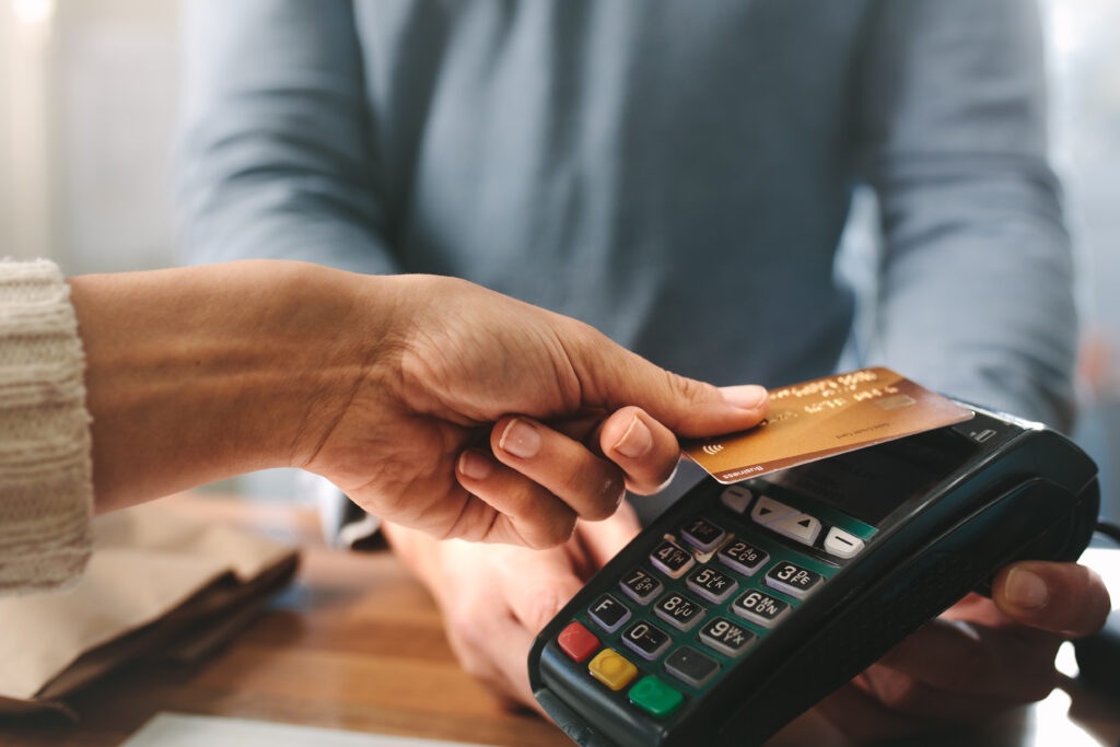 Close-up of a person making a contactless payment with a credit card at a card reader.