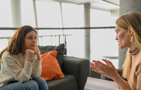 Woman receiving emotional support from a professional during a private conversation in an office setting.