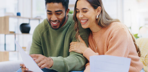 Happy man and woman looking at budgeting sheets