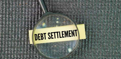 Magnifying glass focusing on the words ‘Debt Settlement’ written on a label