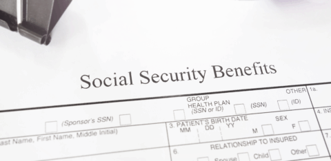 Social Security Benefits form on a desk with a red pen and paperclip.