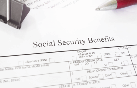 Social Security Benefits form on a desk with a red pen and paperclip.