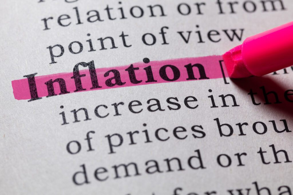 Close-up of the word “inflation” marked with a pink highlighter on a printed page.