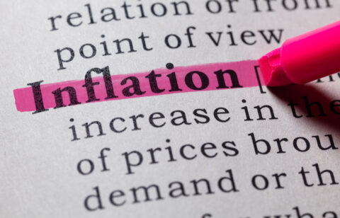 Close-up of the word “inflation” marked with a pink highlighter on a printed page.