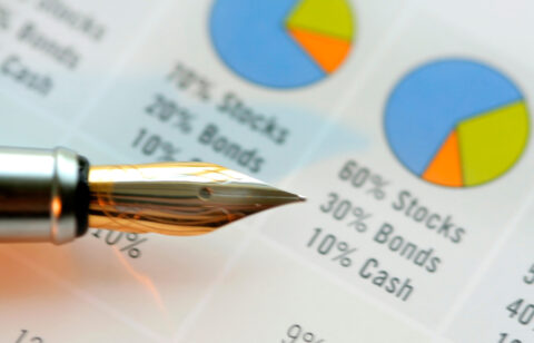Close-up of a fountain pen resting on a financial chart showing stock, bond, and cash allocations.