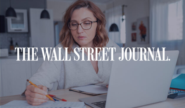 Woman wearing glasses working at a laptop and taking notes at home, with The Wall Street Journal logo overlayed.