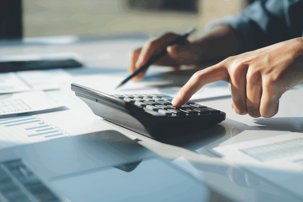 Person using a calculator to review financial documents on a desk.