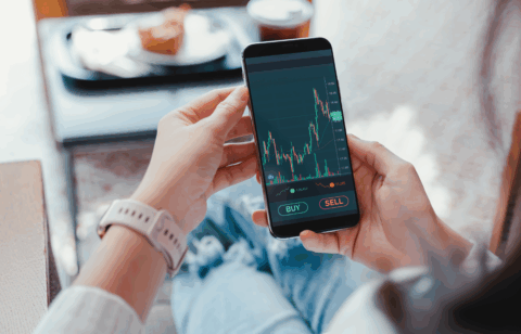 Person holding a smartphone displaying a stock trading app with buy and sell options.