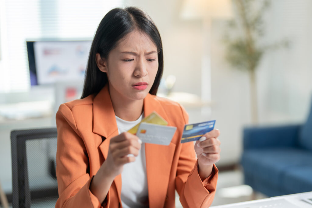 Woman looking concerned while comparing multiple credit cards at her desk.
