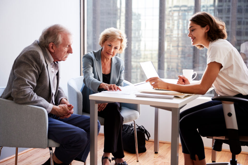 An older couple sits across from a professional in an office, reviewing financial documents together.