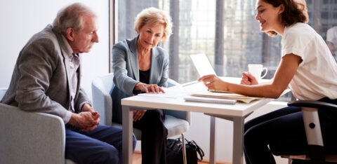 An older couple sits across from a professional in an office, reviewing financial documents together.
