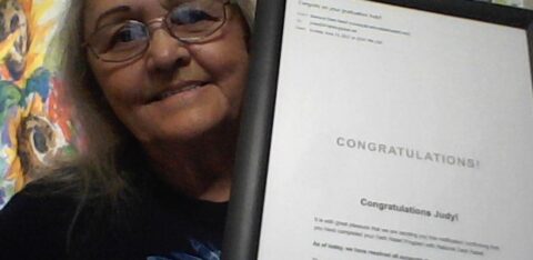 Smiling woman holding a framed congratulatory certificate