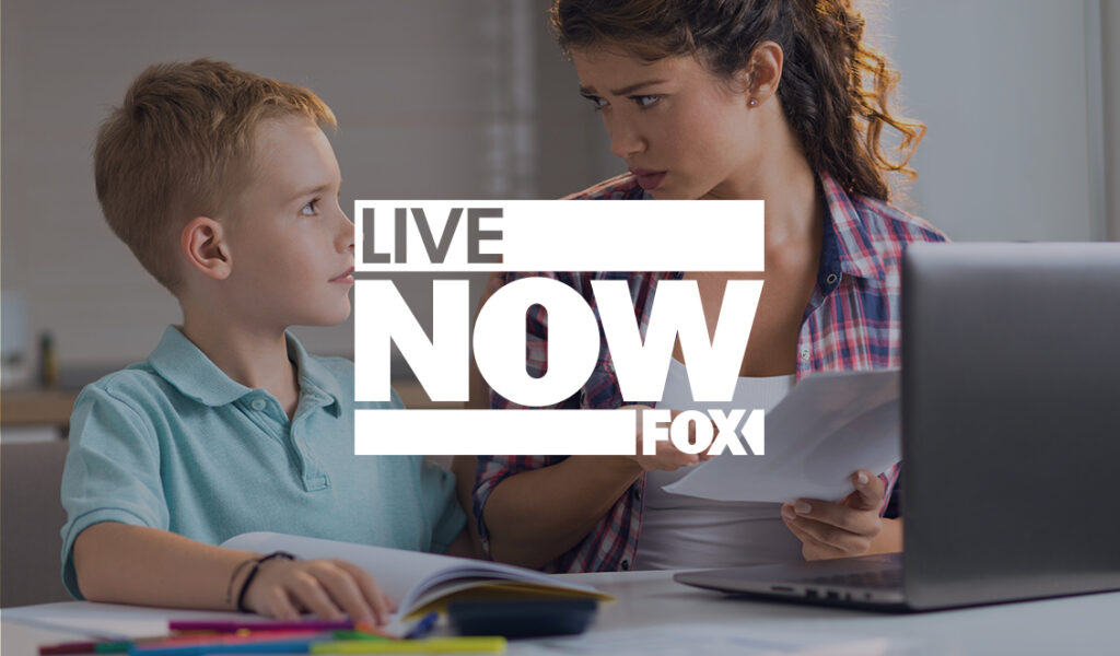 A concerned mother holding bills talks with her young son at a table with a laptop, with the “Live Now FOX” logo overlaid in the center