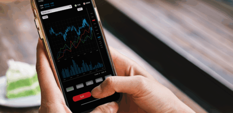 Person using a smartphone to view stock market charts and press the sell button.