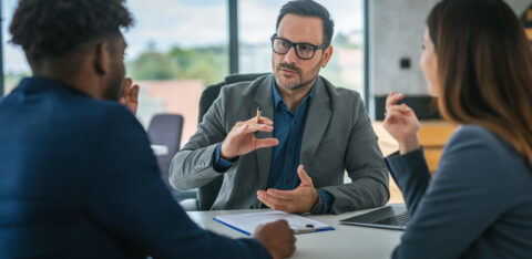 Credit counselor meeting with two clients in an office to discuss financial planning or debt solutions.