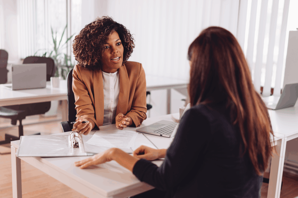 A woman meets with a professional in an office to review documents and discuss information.