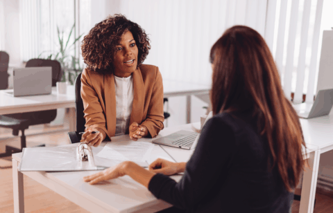 A woman meets with a professional in an office to review documents and discuss information.