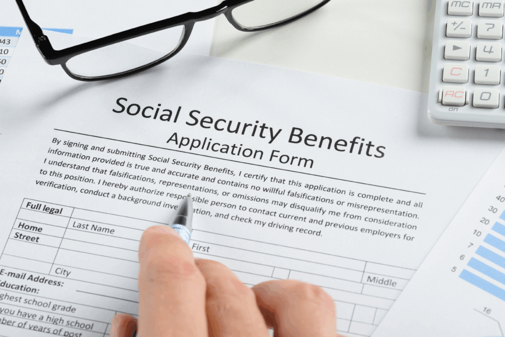 A person reviews a Social Security Benefits application form with a pen and paperwork nearby.