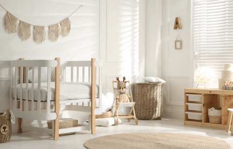 A bright nursery with a white crib, wicker baskets, a stuffed deer toy, and natural wood furniture.