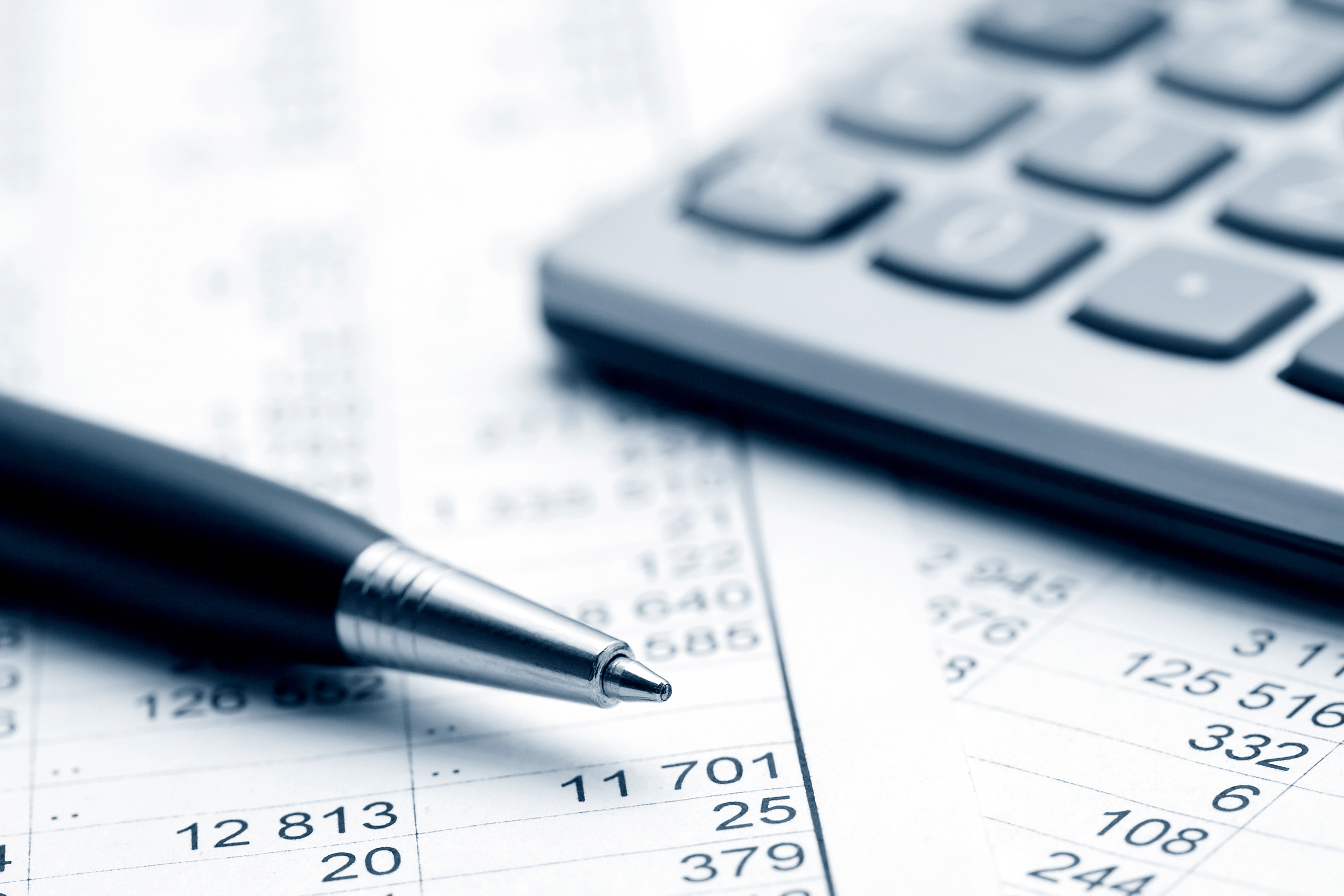 Close-up of a pen and calculator resting on financial documents with numbers.