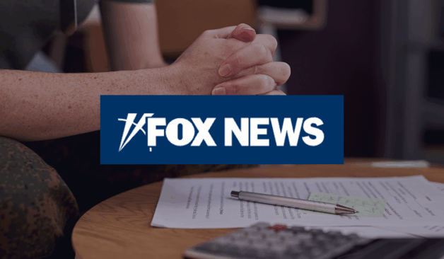 Clasped hands of a person wearing a military uniform resting above paperwork on a table, with a Fox News logo overlaid in the center.