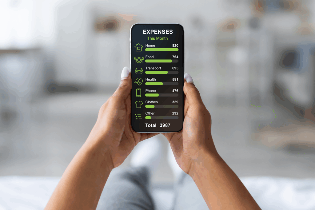 Person holding a smartphone that displays a monthly expense breakdown, including housing, food, transportation, health, phone, clothing, and other costs.