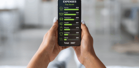 Person holding a smartphone that displays a monthly expense breakdown, including housing, food, transportation, health, phone, clothing, and other costs.