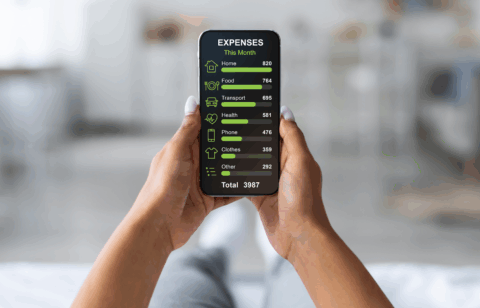 Person holding a smartphone that displays a monthly expense breakdown, including housing, food, transportation, health, phone, clothing, and other costs.
