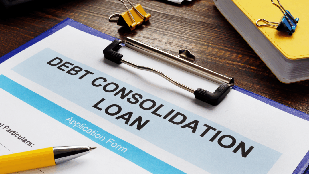 Debt consolidation loan application form on a clipboard, with a pen, calculator, cash, and office supplies on a desk.
