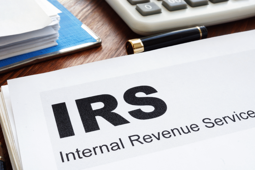Close-up of paperwork labeled “IRS Internal Revenue Service” on a desk with a calculator and pen in the background.