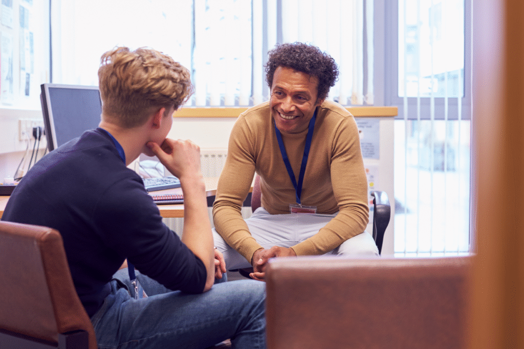 A professional meeting between two individuals in a small office, engaged in a focused and friendly conversation.