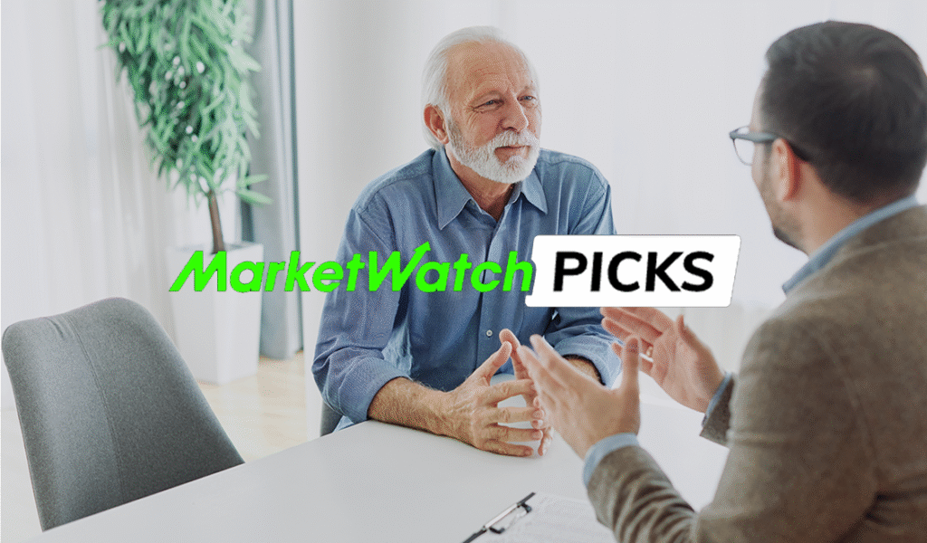 An older man talks with a financial professional across a desk in an office, with the text “MarketWatch Picks” displayed over the image.