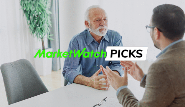 An older man talks with a financial professional across a desk in an office, with the text “MarketWatch Picks” displayed over the image.