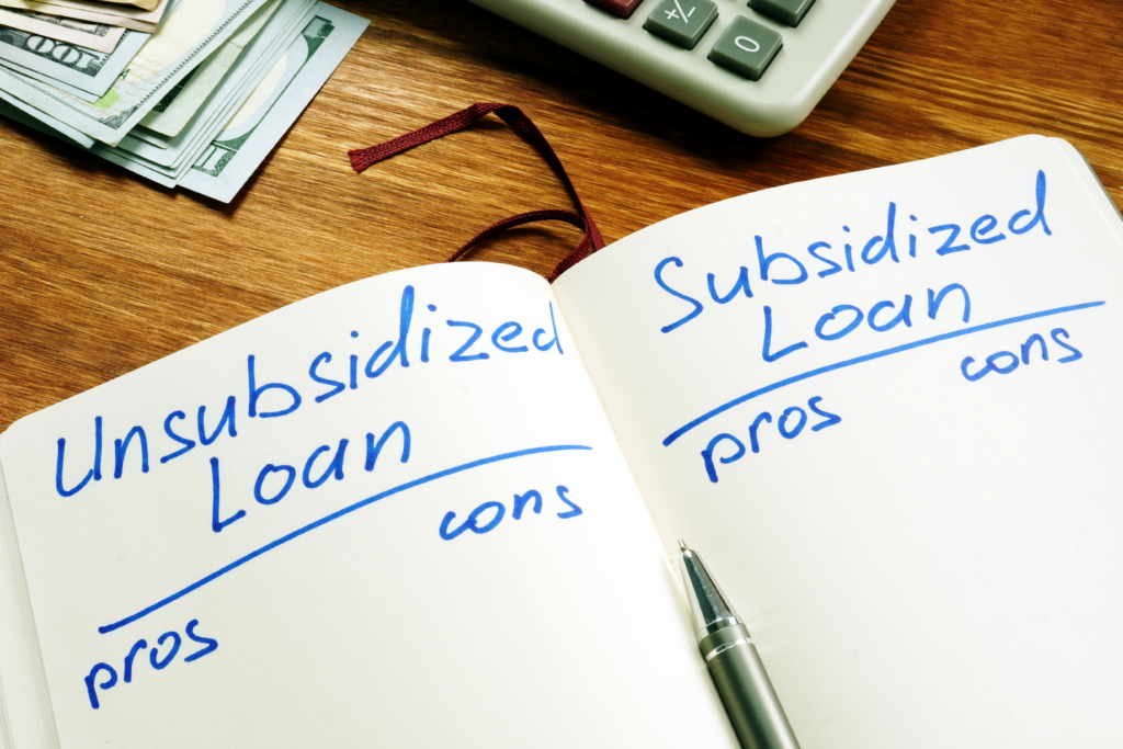 Notebook comparing unsubsidized and subsidized loans with pros and cons, next to cash and a calculator