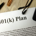Document labeled “401(k) Plan” on a desk with a pen, eyeglasses, and calculator nearby.