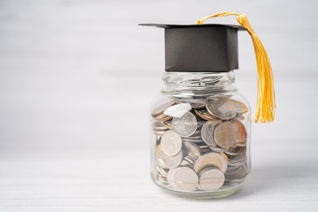 Jar of mixed coins with a black graduation cap and tassel on top