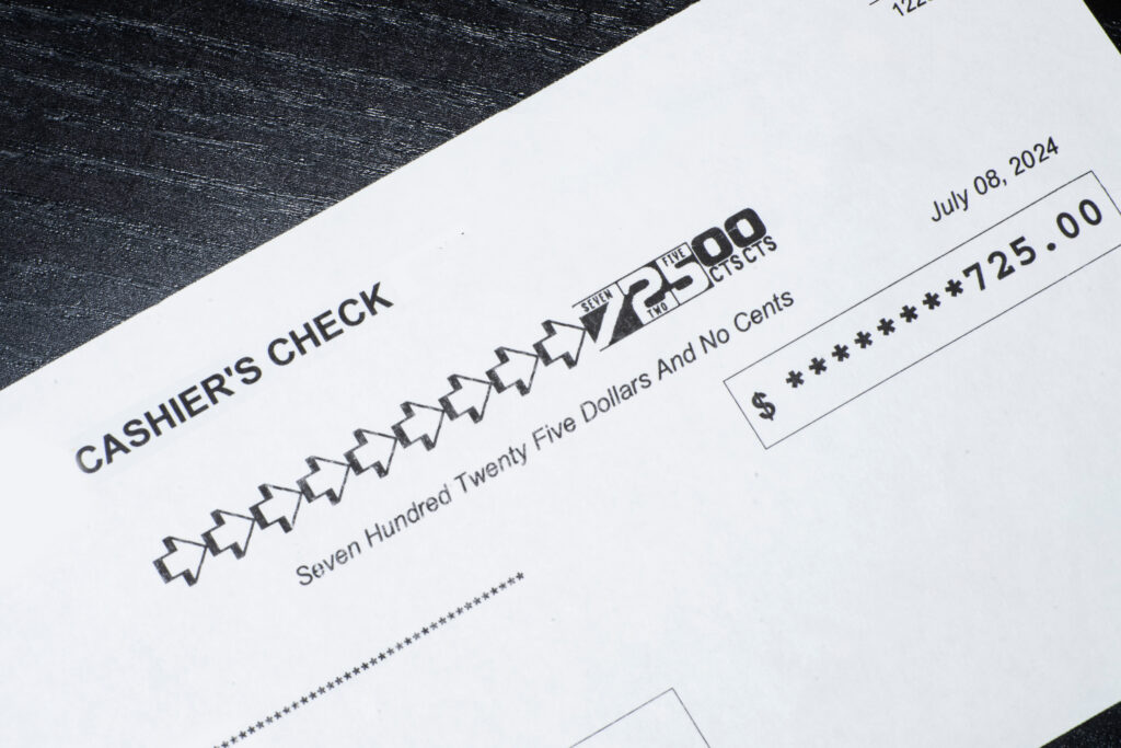 Close-up of a cashier’s check showing a payment amount of $725 with the date printed.
