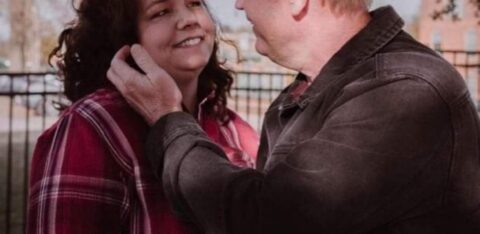 Man and woman sharing a warm moment outside, with the man holding the woman’s cheek as they smile at each other.