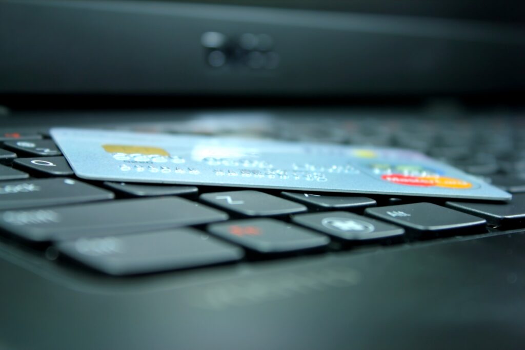 Credit card placed across computer keys, with a blurred laptop screen in the background.