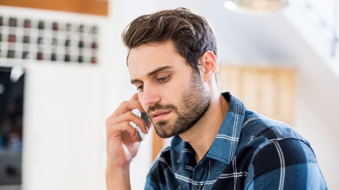 Person talking on a smartphone with a serious expression while seated indoors