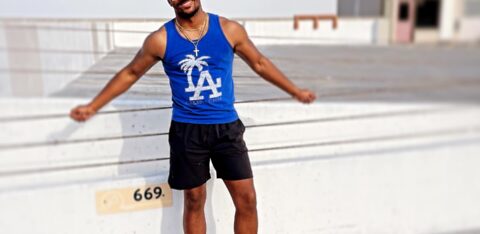 Man standing on a rooftop parking area, smiling and leaning back against a concrete barrier